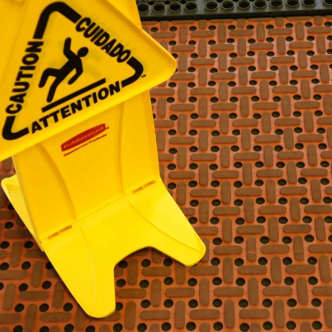 Grease-Resistant Rubber Mat red color placed on slippery surface with yellow caution board