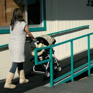 Woman moving a baby carriage up a ramp that has corrugated ramp cleat rubber runners