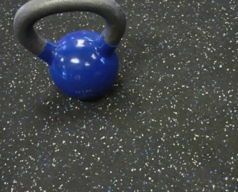 Blue Dot Recycled Rubber Roll placed on Gym Floor with Dumbell on top