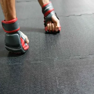 Bumpy mats connected together with a man holding his fists striahgt on it with boxing gloves on