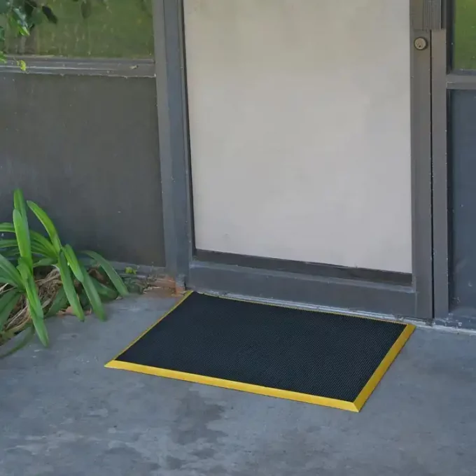 Doormat with yellow border placed in front of door
