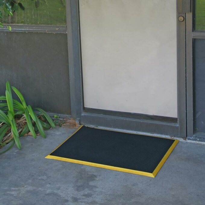 Doormat with yellow border placed in front of door