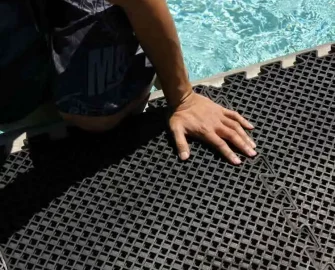 Someones hand on top of a eco drain tile next to a swimming pool