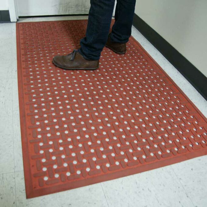 Orange kitchen mat underneath a person standing on it with brown shoes