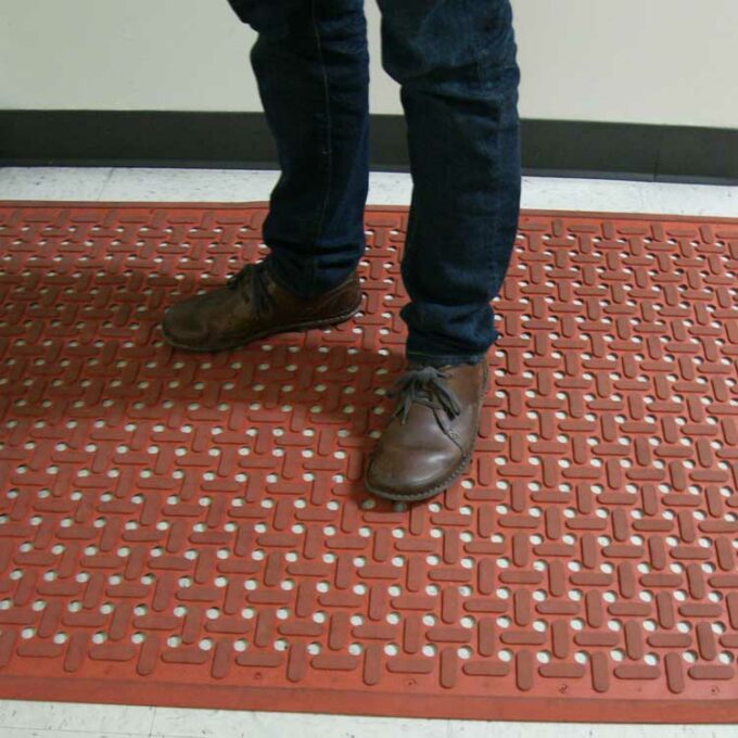 Orange kitchen mat underneath a person with brown shoes