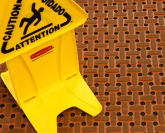 Grease-Resistant Rubber Mat red color placed on slippery surface with yellow caution board