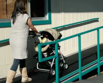 Woman moving a baby carriage up a ramp that has corrugated ramp cleat rubber runners
