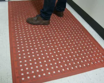 Orange kitchen mat underneath a person standing on it with brown shoes