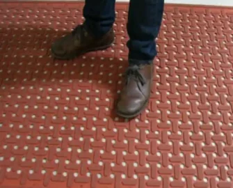 Orange kitchen mat underneath a person with brown shoes
