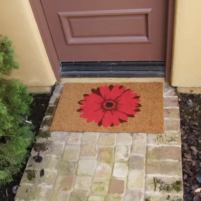 Doormat with welcome message and a field of red daisies