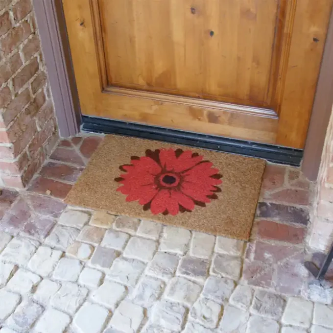 Doormat with welcome message and a field of red daisies