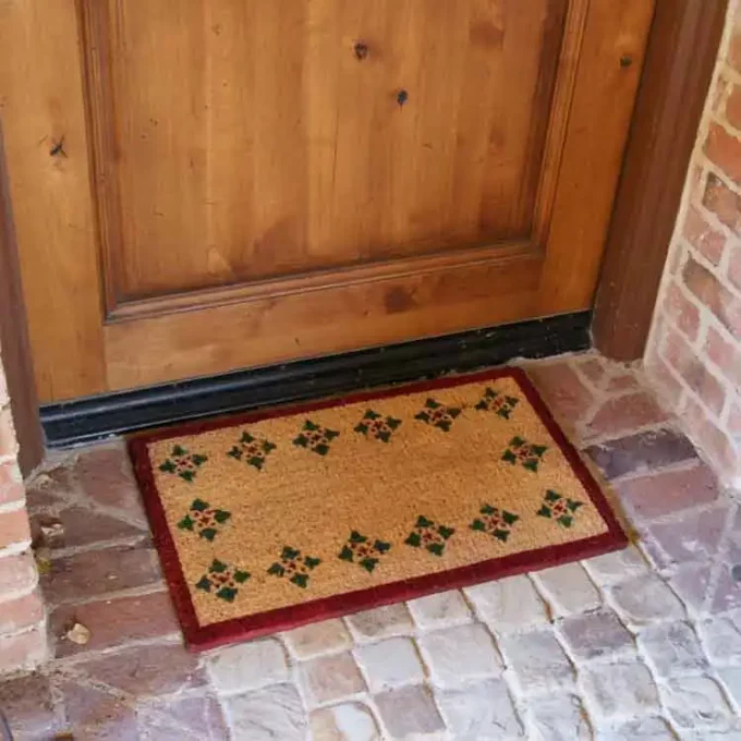 Brown mat with 4 triangles along its perimeter next to a door entrance