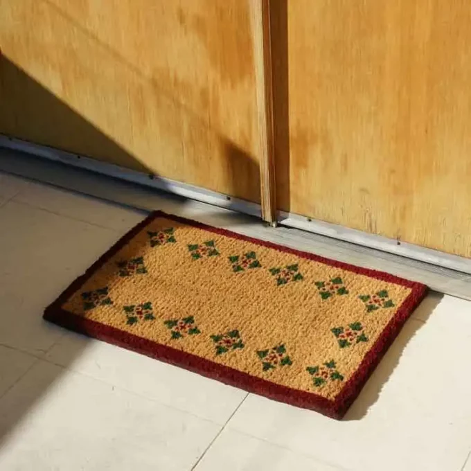 Brown mat with green triangle pattern along the perimeter next to a door entrance