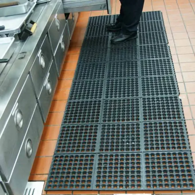 A person is standing on black color dura chef drainage mat