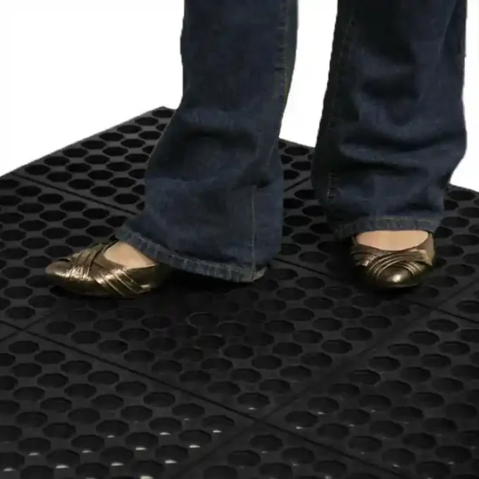 A person is standing on black color dura chef drainage mat