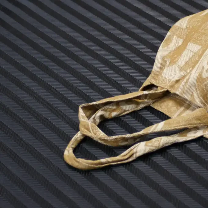 Black rubber mat with a brown bag on the ground