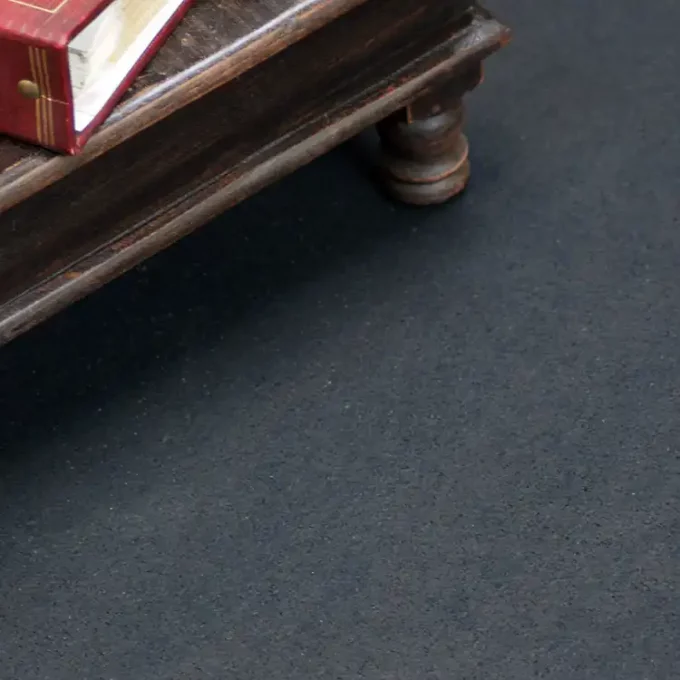 Black floormat with a table on top and a book
