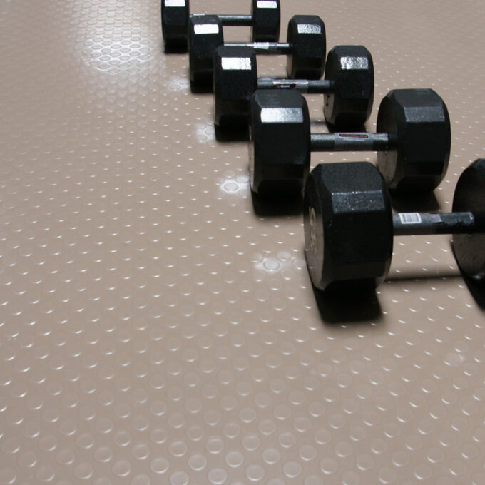 Coin or Stud Top Textured Flooring in beige color placed on gym floor with some weight placed on it