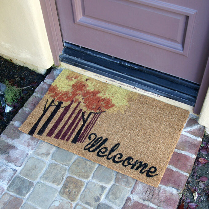 Mat that has colorful fall trees inside with a Black text saying welcome